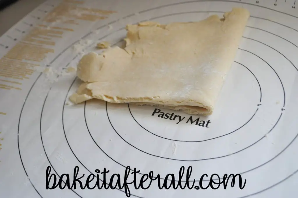 gluten free pie dough folded into fourths on a pastry mat