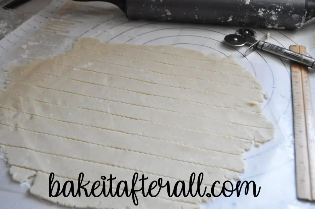 gluten free pie dough cut into strips with fluted edges for a lattice topped pie on a pastry mat