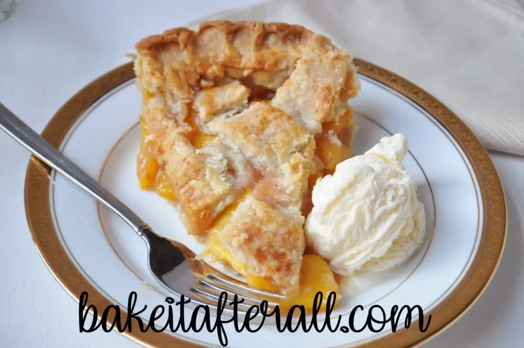 slice easy fresh peach pie on a plate with a scoop of vanilla ice cream and a fork
