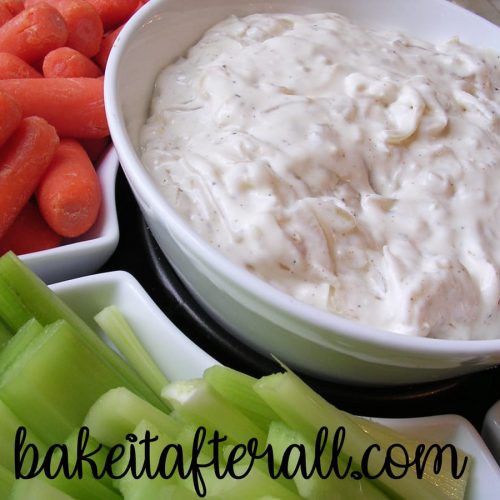pan fried onion dip in a bowl with carrots and celery surrounding