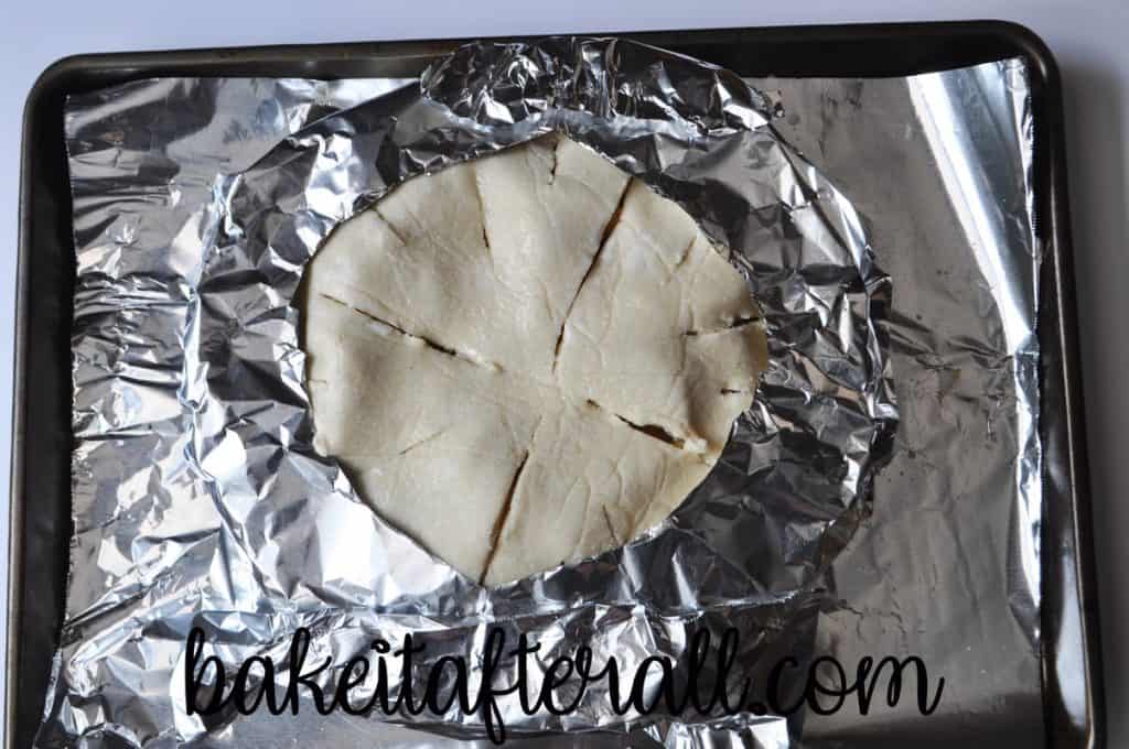 aluminum foil ring on an unbaked pie on an aluminum foil lined baking sheet