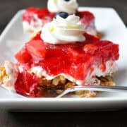 a piece of strawberry pretzel jello saald on a white plate with a bite on a fork