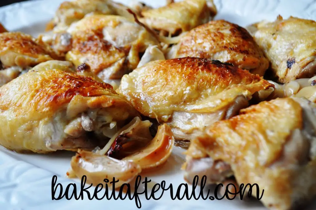 roasted chicken on a platter with roasted garlic and shallots