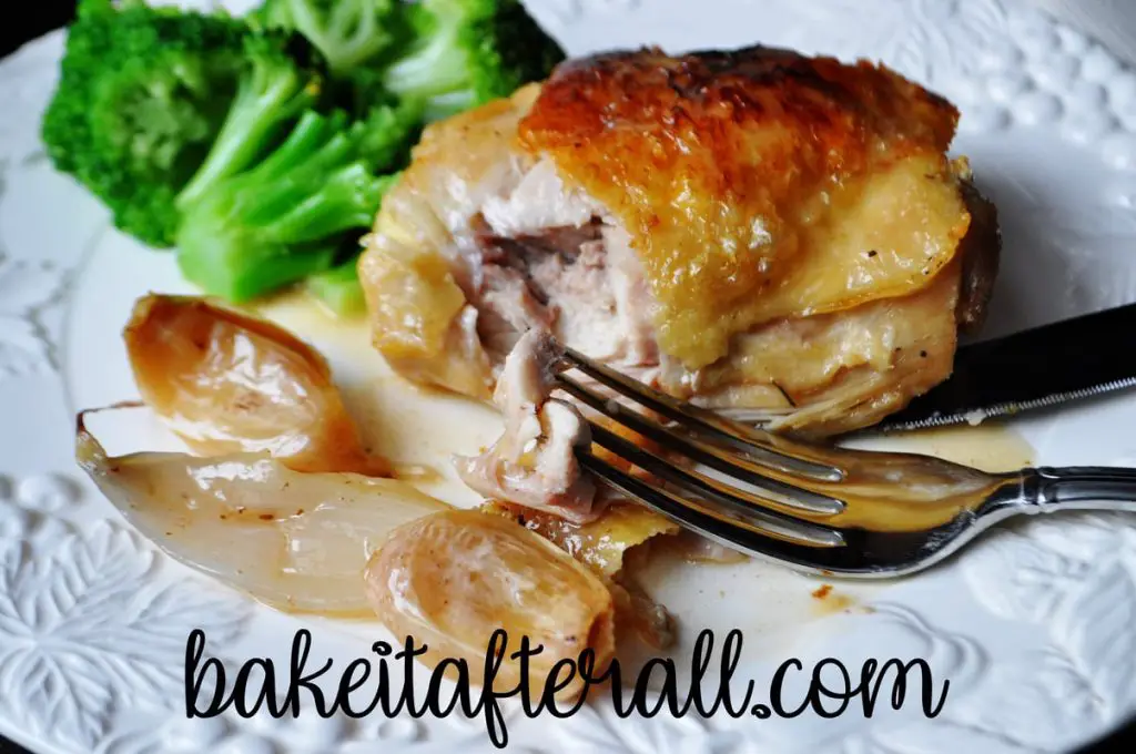 up close of roasted chicken with garlic pan sauce on a plate with a fork