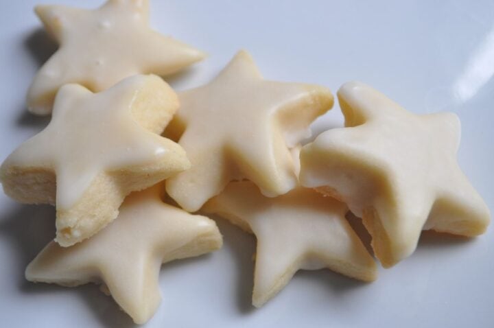 iced vanilla shortbread cookies cut into star shapes on a white plate