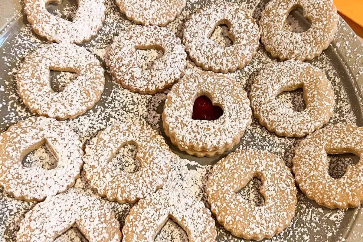 a plate of Linzer cookie top cookies with one sandwiched cookie in the center