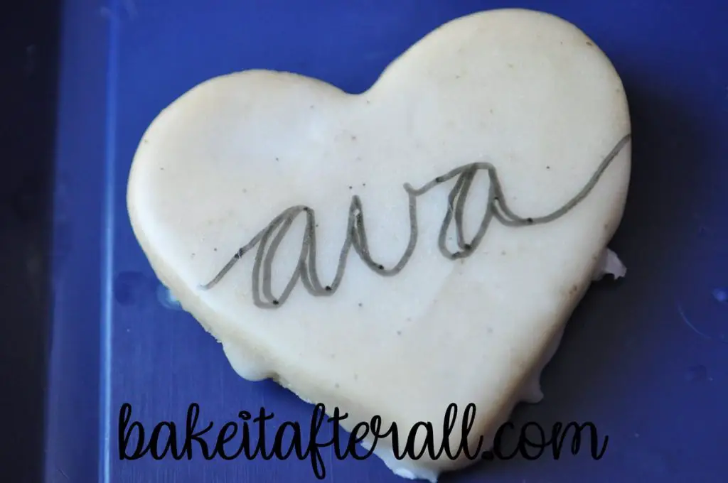 "ava" on a cookie with lines drawn down for calligraphy