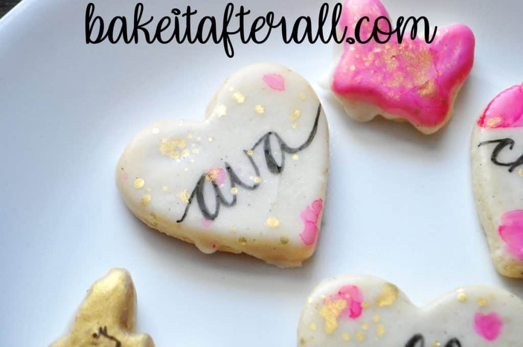 cookie that says "Ava" in calligraphy and splattered with gold luster dust