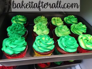 green frosted cupcakes in a cake pan for transporting