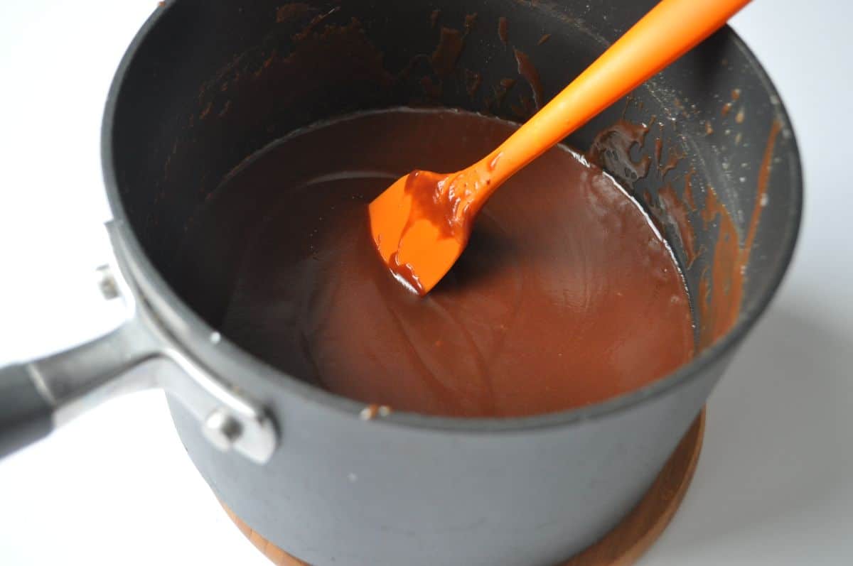 hot fudge in a saucepan with a small silicone spatula to stir