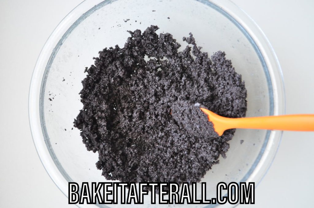 gluten free chocolate sandwich cookie crumbs in bowl with small silicone spatula