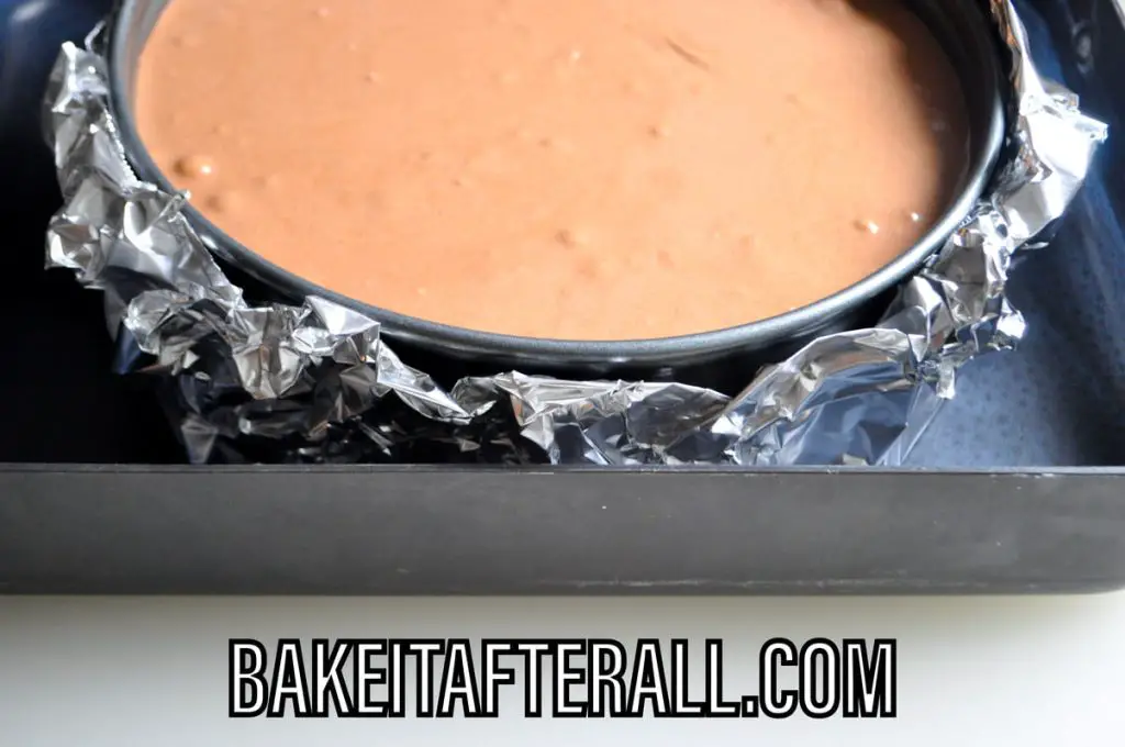 cheesecake batter inside springform pan in a water bath