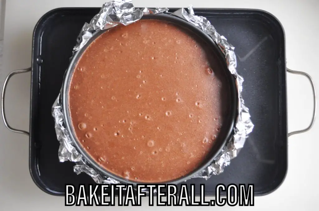 baked cheesecake in springform pan inside a water bath