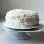 a white coconut cake on a white platter with a white background