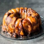 a bundt pan shaped loaf of Monkey Bread on a glass plate on top of a wood surface