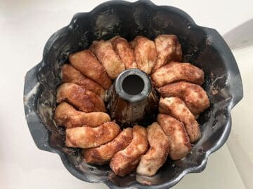 slices of bread dough covered in cinnamon sugar stacked together in a Bundt pan