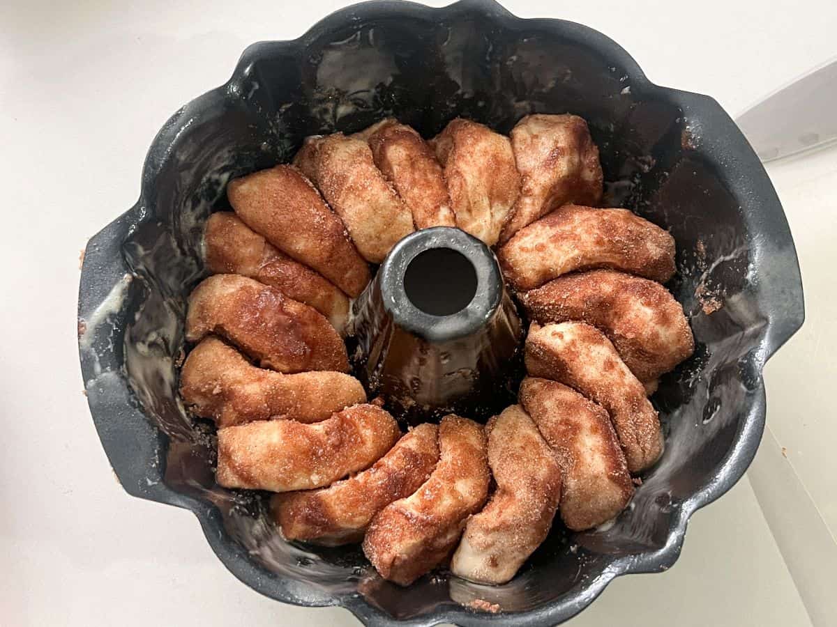 slices of bread dough covered in cinnamon sugar stacked together in a Bundt pan