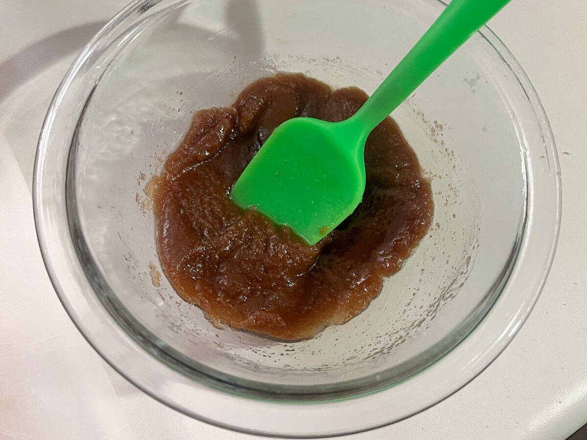 brown sugar and melted butter in a glass bowl with a green silicone spatula