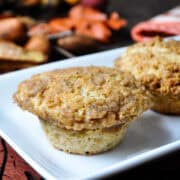 allspice crumb muffins on a white platter with fall leaves in the background