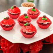 a white platter with cupcakes decorated like apples