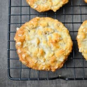 a chewy coconut oatmeal cookie on a black wire cooling rack on top of a dark wood surface