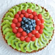 Fresh Fruit Tart on a clear platter with kiwi, raspberries, and blueberries