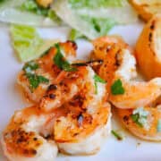 grilled shrimp on a plate with spicy lemon garlic sauce on top