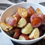a bowl of roasted red potatoes on a placemat