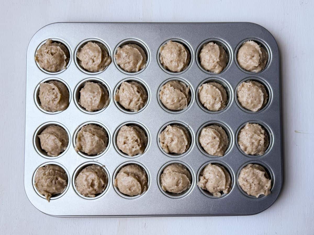 cinnamon sugar donut muffin batter scooped into a mini muffin pan