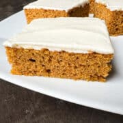 pumpkin cake with cream cheese frosting on a white platter