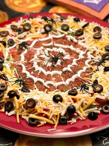 spider web taco dip on a platter on top of a Halloween table
