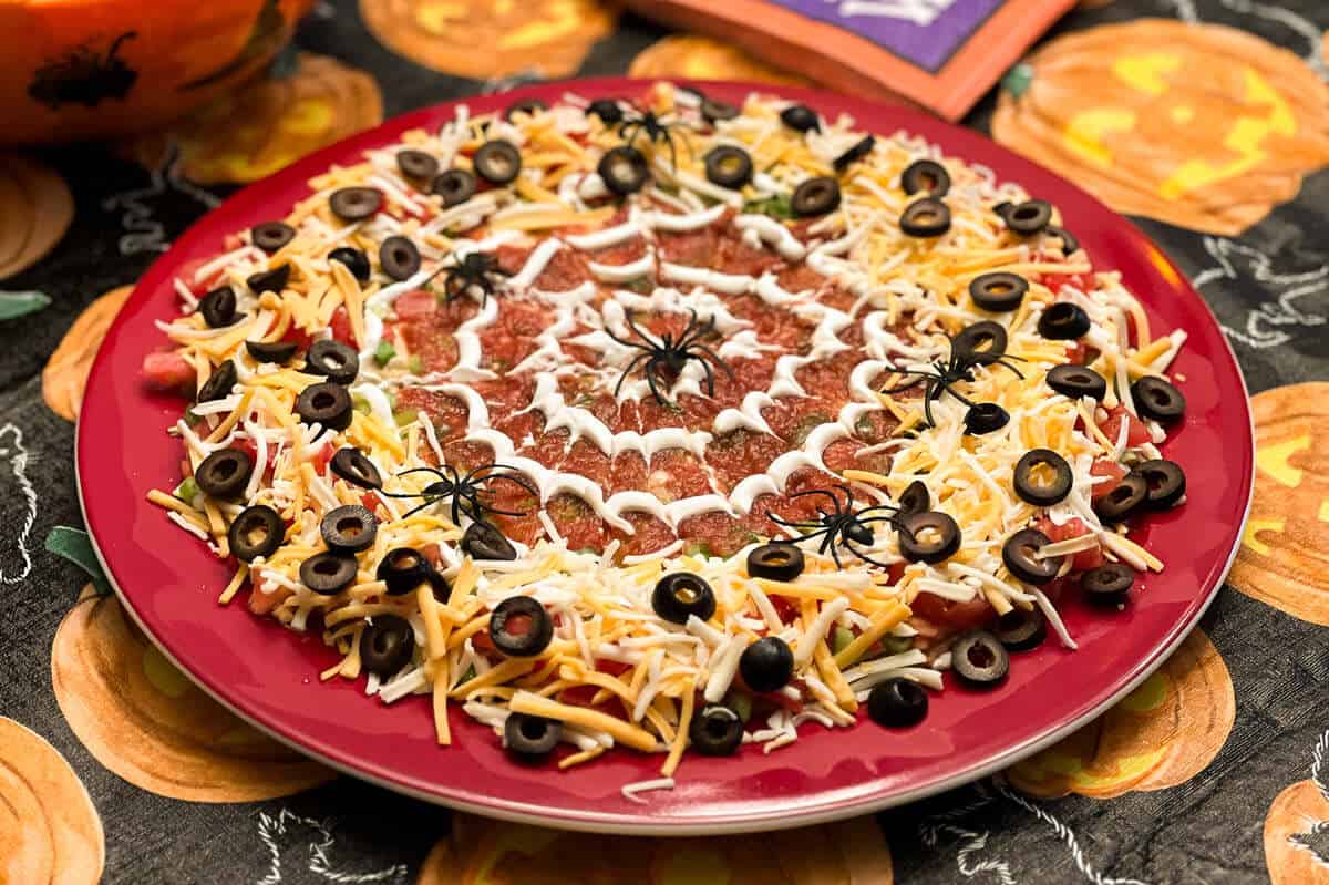 spider web taco dip on a platter on top of a Halloween table