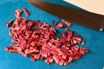 turkey bacon cut into pieces on a blue cutting mat
