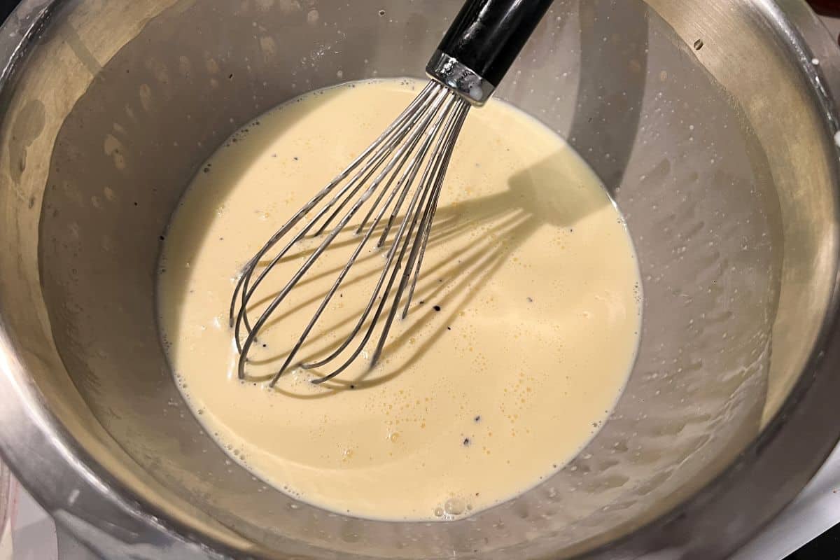 egg custard in a bowl with a wire whisk