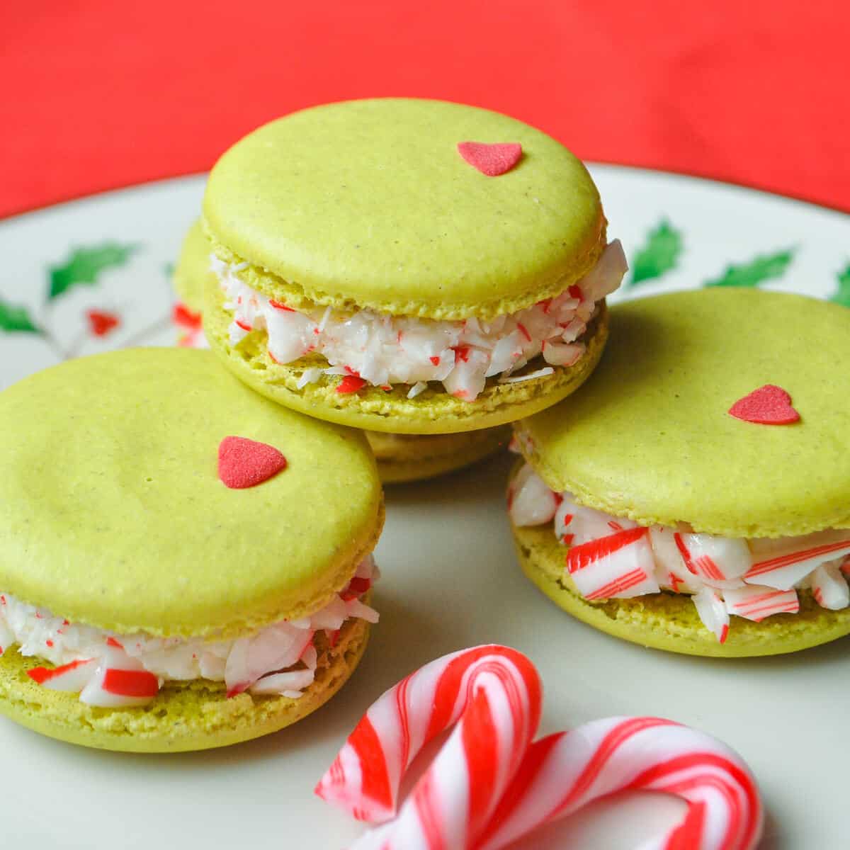 Nut Free Grinch Macarons on a plate with peppermint candy canes