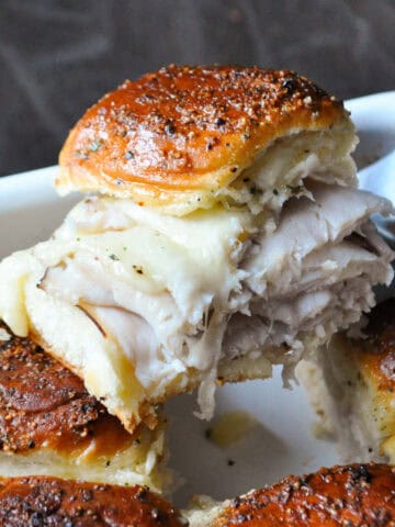 a baked Hawaiian sandwich being lifted out of a dish with a spatula