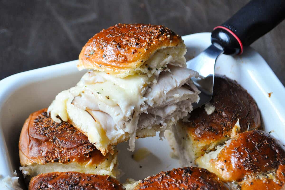 a baked Hawaiian sandwich being lifted out of a dish with a spatula
