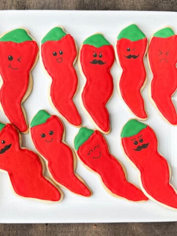sugar cookies decorated like chili peppers with funny faces drawn on