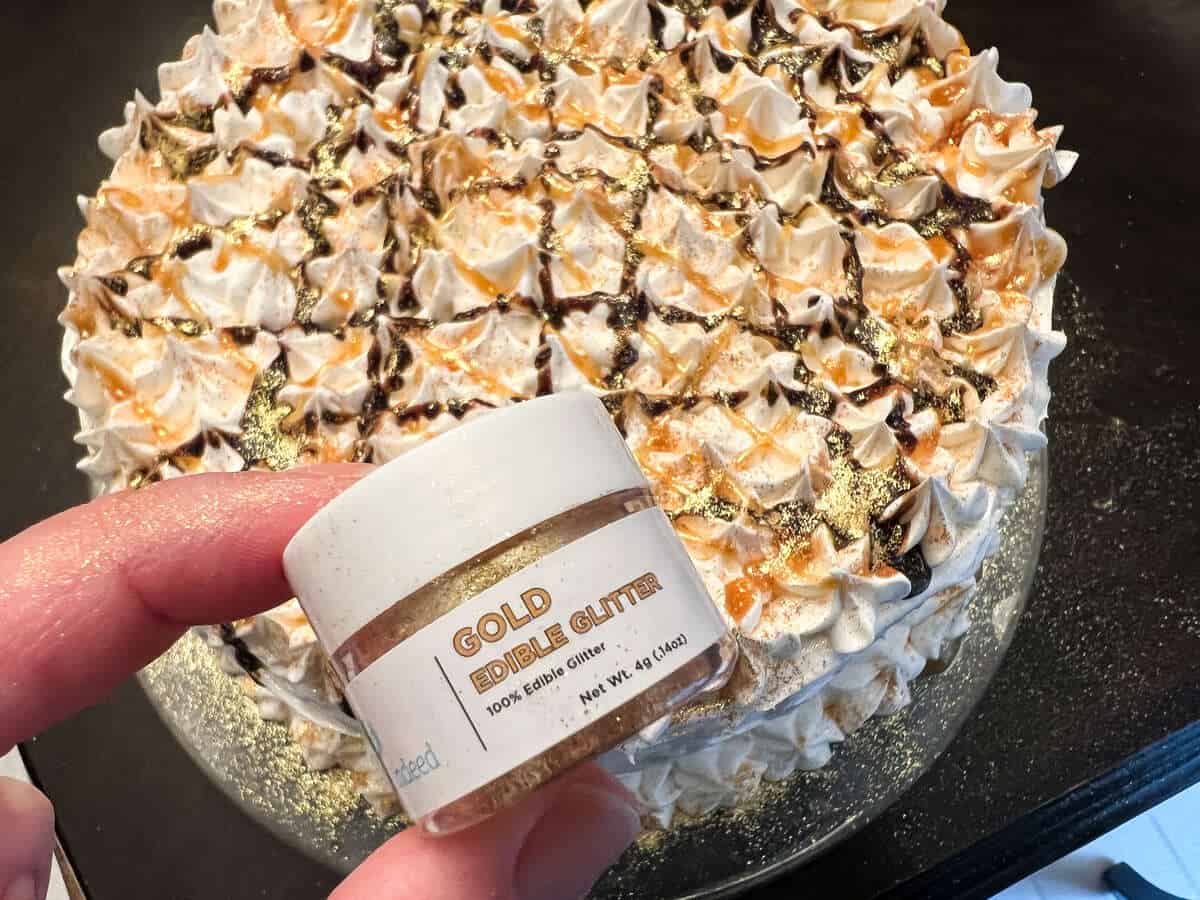 a container of edible gold glitter held up in front of an ice cream cake