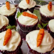 carrot cupcakes with cream cheese frosting on a platter decorated with nut free marzipan carrots