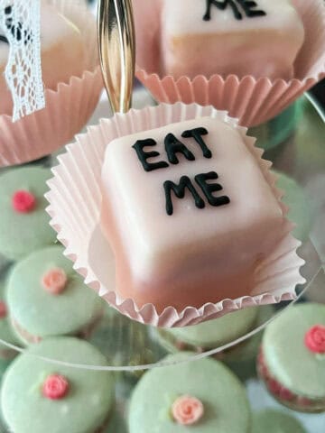 Alice in Wonderland petit fours that say "Eat Me" inside pink cupcake liners