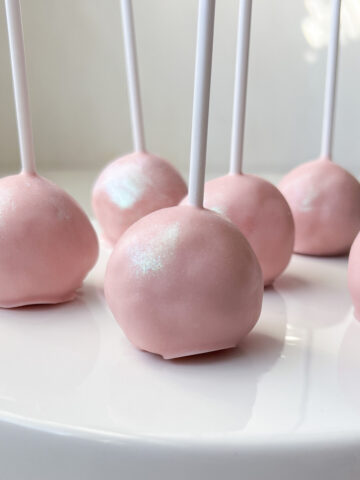 light pink cake pops on a white cake stand