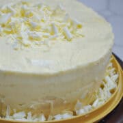 white chocolate amaretto cake with white chocolate curls around the base of the cake and on top
