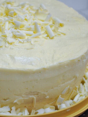 white chocolate amaretto cake with white chocolate curls around the base of the cake and on top