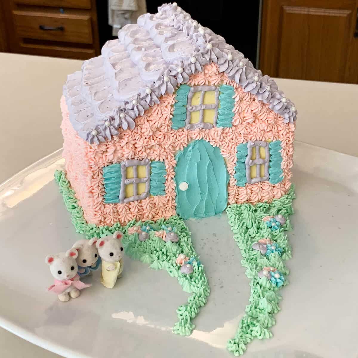 a cute Cottage House Cake on a white cake stand