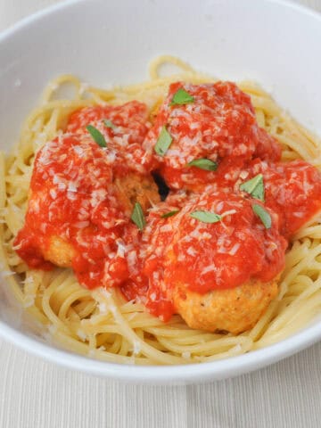 a bowl of spaghetti and healthy baked chicken meatballs covered in marinara sauce