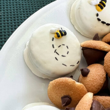 a bee and black dashes on a white fudge covered Oreo