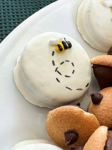 a bee and black dashes on a white fudge covered Oreo
