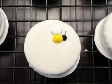 a bee made of royal icing on a white fudge covered Oreo