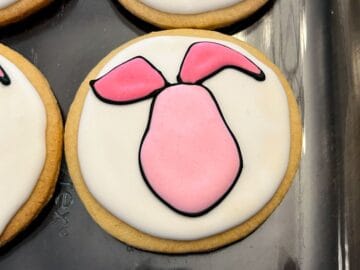 dark pink royal icing filling the ears of a piglet face cookie